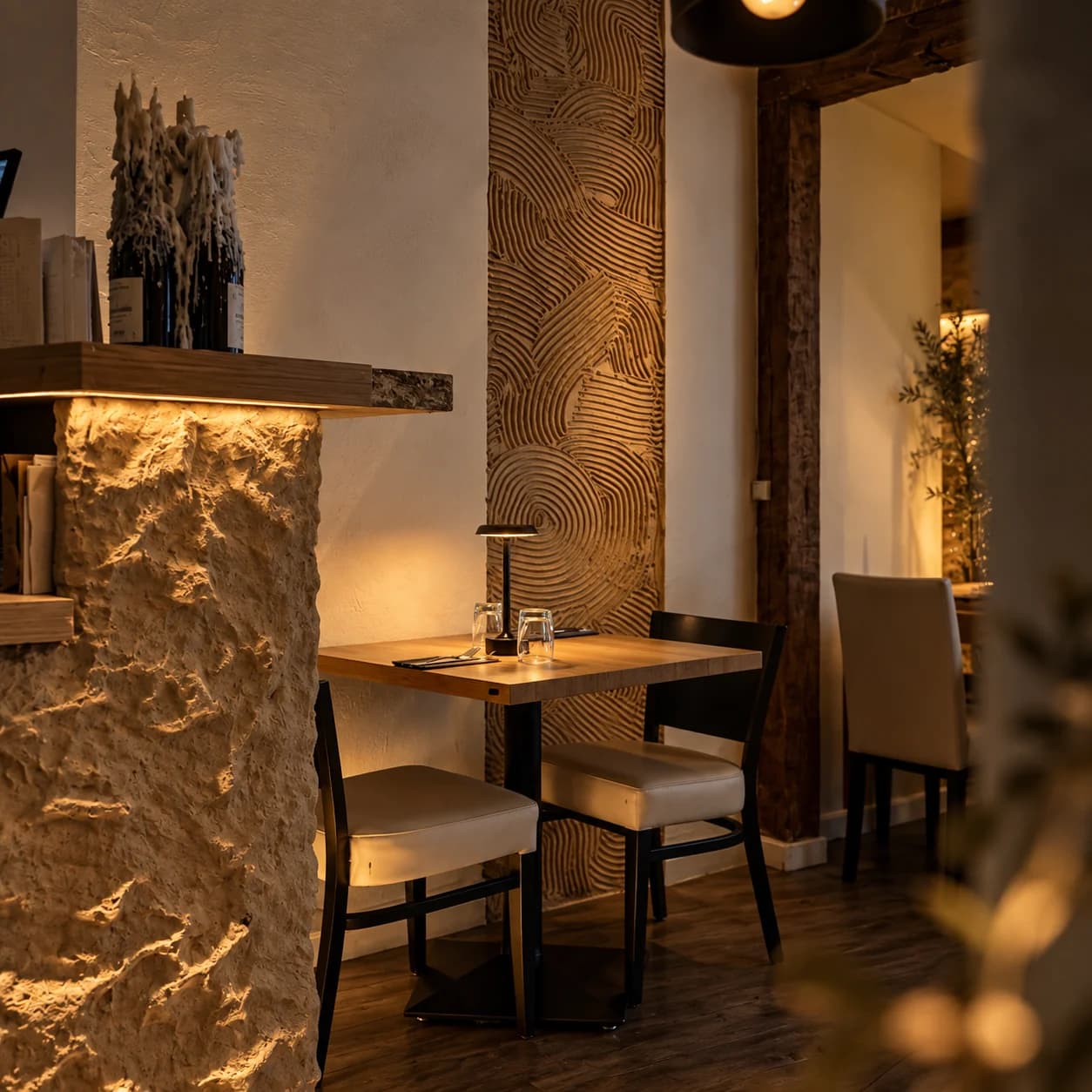 Una mesa íntima, piedra iluminada y madera en la sala de NOMADE